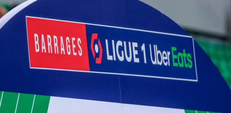 Signboard on a blue stadium arch reading 'BARRAGES' and 'LIGUE 1 Uber Eats' with red and green highlights