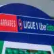 Signboard on a blue stadium arch reading 'BARRAGES' and 'LIGUE 1 Uber Eats' with red and green highlights