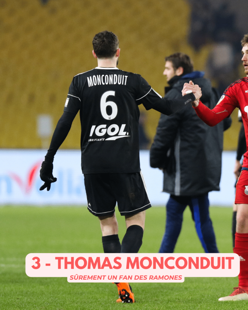 Back view of a soccer player in a black kit with 'MONCONDUIT' and number 6, shaking hands with a teammate on the field; caption at bottom reads '3 - THOMAS MONCONDUIT'