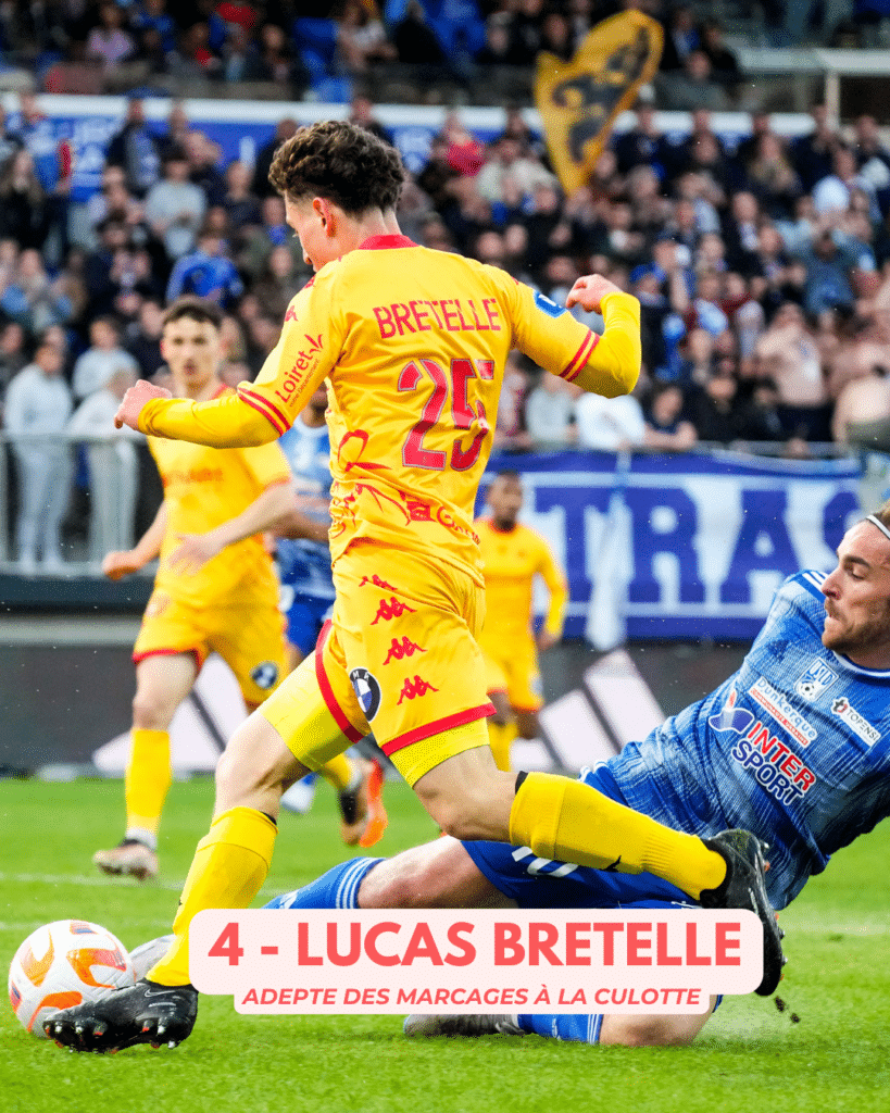 Soccer player in a yellow kit, number 25 Bretelle, controls the ball while a blue-clad defender slides in during a match; crowd in the stands behind.