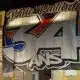 Nighttime street view: a large white banner with bold black outline '34' and colorful red/blue accents covering a building fa&ccedil;ade.