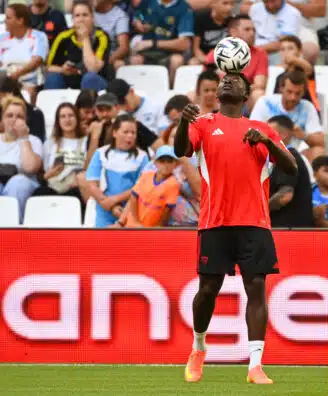 Akor Adams Olympique de Marseille v Seville FC - Match Amical 02082025 | AllezPaillade.com Soccer player in red jersey heads the ball with crowds watching in the stands behind.