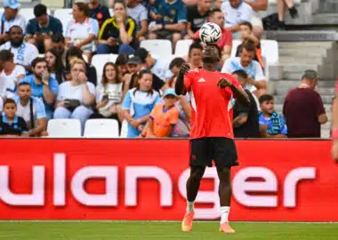 Akor Adams Olympique de Marseille v Seville FC - Match Amical 02082025 | AllezPaillade.com Soccer player in red jersey heads the ball with crowds watching in the stands behind.