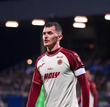 Male soccer player in a white and maroon jersey on the field, looking focused during a match.