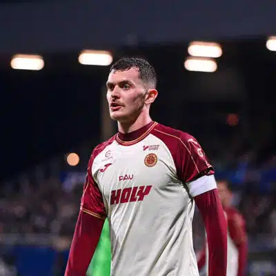 Male soccer player in a white and maroon jersey on the field, looking focused during a match.