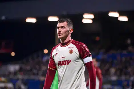 Male soccer player in a white and maroon jersey on the field, looking focused during a match.