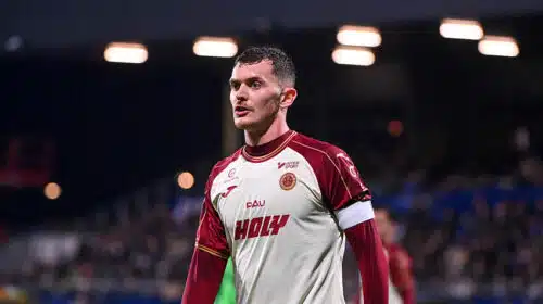 Male soccer player in a white and maroon jersey on the field, looking focused during a match.