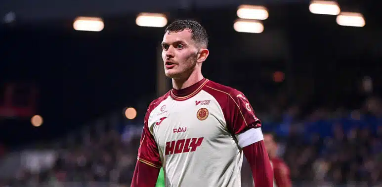 Male soccer player in a white and maroon jersey on the field, looking focused during a match.