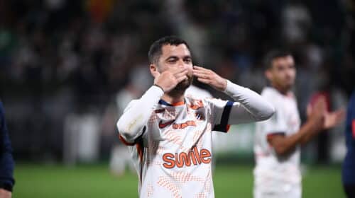 Soccer player in a white jersey celebrating, blowing a kiss with hands to lips on the field