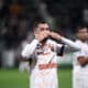 Soccer player in a white jersey celebrating, blowing a kiss with hands to lips on the field