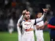 Soccer player in a white jersey with orange pattern, giving two thumbs up on the field.