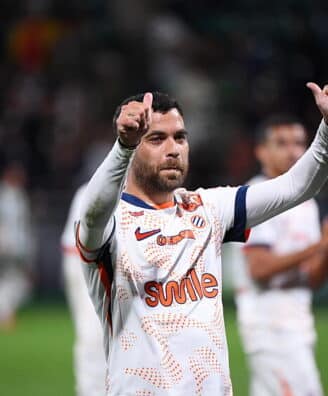 Teji SAVANIER of - Photo by Icon Sport | AllezPaillade.com Soccer player in a white jersey with orange pattern, giving two thumbs up on the field.