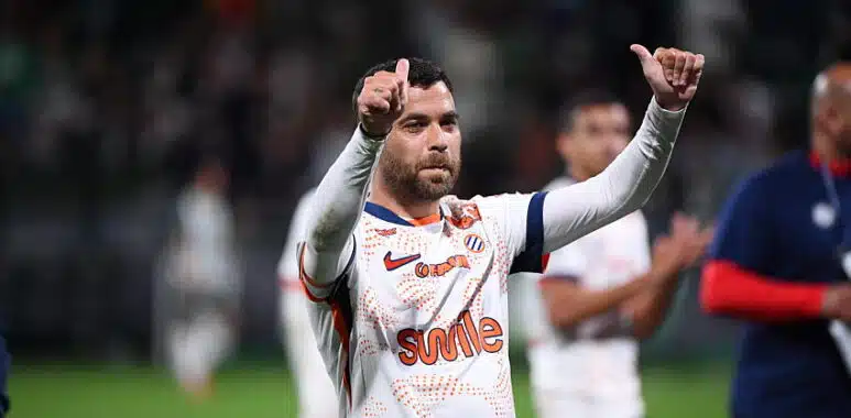 Teji SAVANIER of - Photo by Icon Sport | AllezPaillade.com Soccer player in a white jersey with orange pattern, giving two thumbs up on the field.