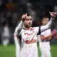 Soccer player in a white jersey with orange pattern, giving two thumbs up on the field.