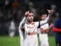 Soccer player in a white jersey with orange pattern, giving two thumbs up on the field.