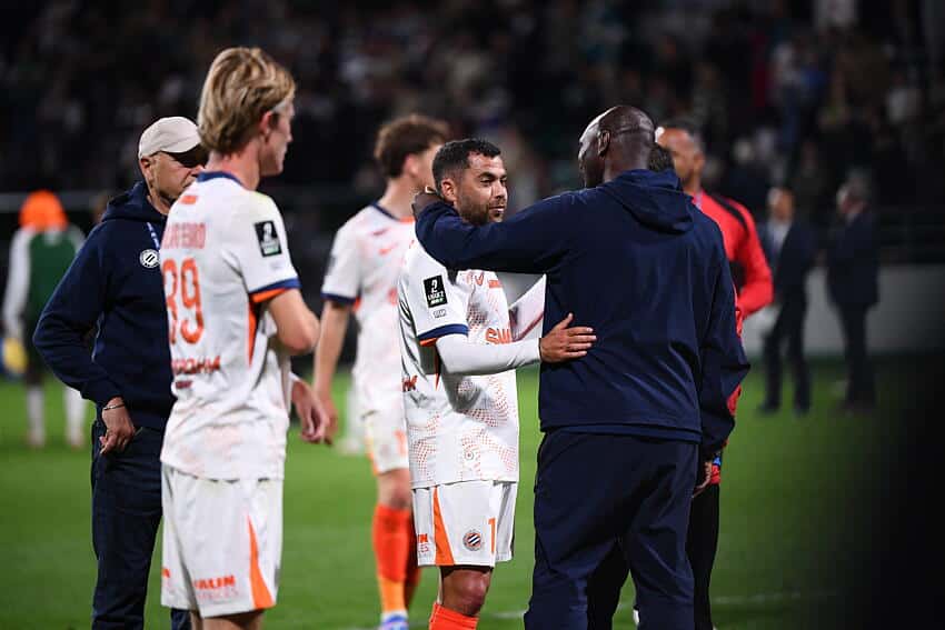 Teji SAVANIER Camara of - Photo by Icon Sport | AllezPaillade.com Soccer players on the field share a hug and handshake after a match, with a central player in a white jersey being consoled by a teammate in a dark jacket.
