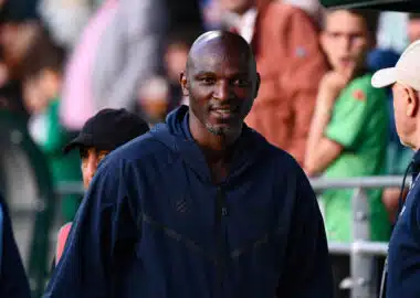 Zoumana Camara Red Star FC v Montpellier Herault SC - Ligue 2 BKT 20252026 | AllezPaillade.com Man in a navy jacket smiles as he stands at an outdoor event, with blurred crowd members in the background.