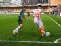 Two soccer players contest the ball near the sideline on a green pitch as a white jersey #44 (Chennai) clashes with a green opponent, with stands and crowd in the background.