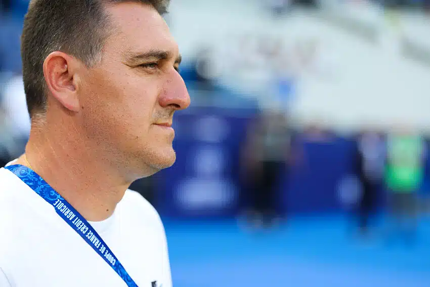 Rodriguez | AllezPaillade.com Man in a white shirt shown in profile, wearing a blue lanyard at a sports arena or venue.