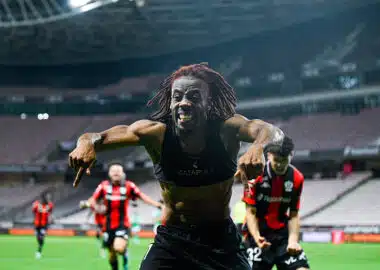 Elie Wahi | AllezPaillade.com Soccer player with dreadlocks celebrates toward the camera on a stadium field, arms outstretched and smiling.