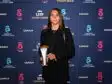 Young woman in a black blazer holding an award on a blue sponsor backdrop (logos include Canal+, Arkema, and Troph&eacute;es).