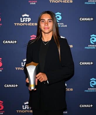 Young woman in a black blazer holding an award on a blue sponsor backdrop (logos include Canal+, Arkema, and Troph&eacute;es).