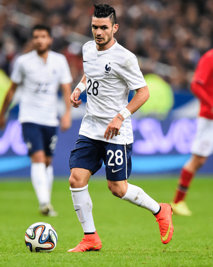 French national team player in a white jersey (number 28) dribbling a soccer ball on the pitch.