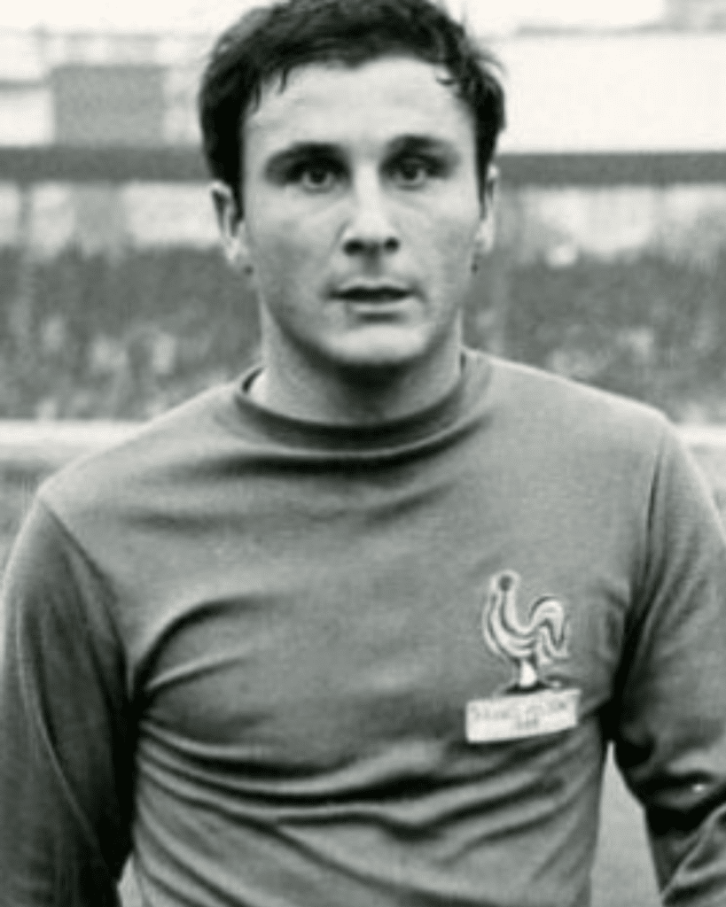 Man wearing a France national team shirt with the rooster emblem, standing outdoors.