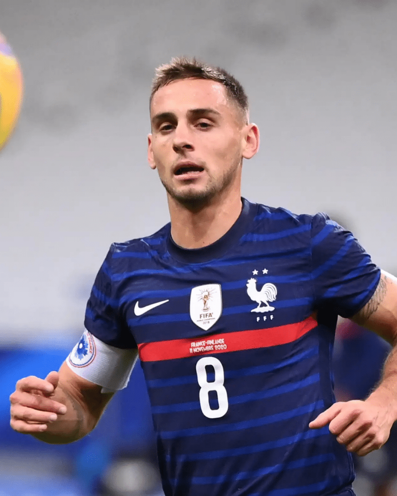 French national team footballer wearing blue jersey with number 8, sprinting on the pitch.