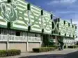 Green and white stadium fa&ccedil;ade with large stylized letters and arches along the front.