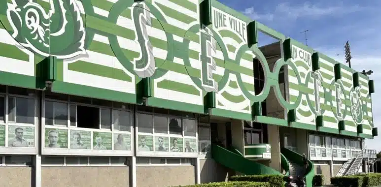 Green and white stadium fa&ccedil;ade with large stylized letters and arches along the front.
