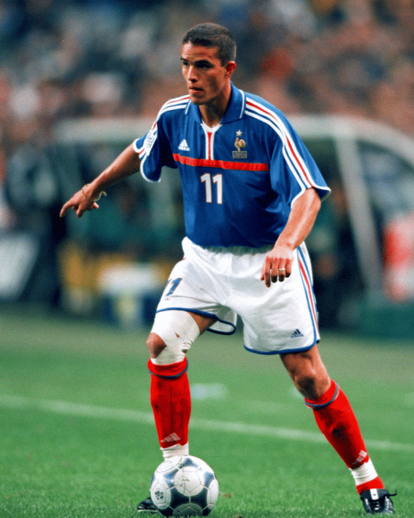 Soccer player in a blue France jersey (number 11) dribbling a ball on the field.