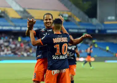 Boudebouz #10 celebrating with a teammate on the soccer field in blue and orange kit.