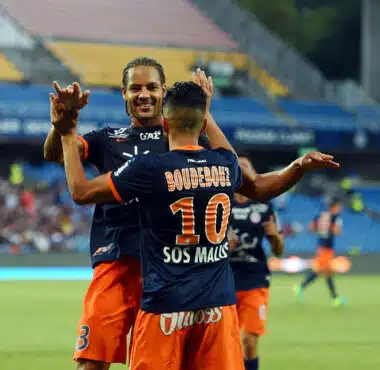 Boudebouz #10 celebrating with a teammate on the soccer field in blue and orange kit.