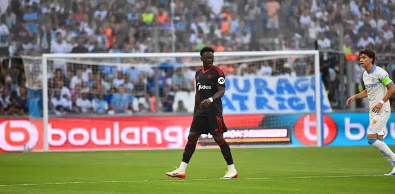 Akor Adams Olympique de Marseille v Seville FC - Match Amical 02082025 | AllezPaillade.com Soccer match scene with a Black player in a black kit with red trim in the foreground, crowd in the stands behind the goal.