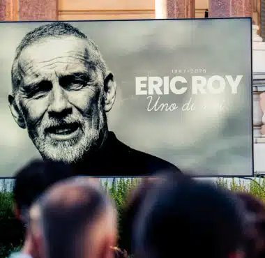 Large outdoor billboard featuring a black-and-white portrait of Eric Roy, with the text '1967-2026 ERIC ROY Uno di moi' on a gray background.