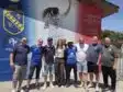 Screenshot | AllezPaillade.com Group of ten people posing together in front of a colorful mural with a football club crest on the wall behind them on a sunny day.