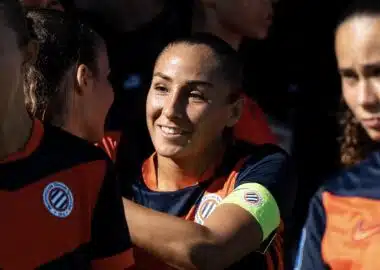 Screenshot | AllezPaillade.com Women’s soccer team celebrates, central player smiles while teammates hug.