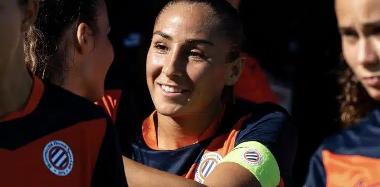 Screenshot | AllezPaillade.com Women’s soccer team celebrates, central player smiles while teammates hug.
