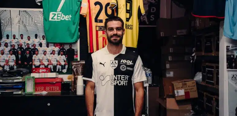 IMG_5121 | AllezPaillade.com Man in a black-and-white football jersey standing in a team shop with jerseys hanging behind him.