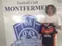 Young man with curly hair posing beside a large Football Club Montfermeil sign, holding a navy and orange Montfermeil football jersey.