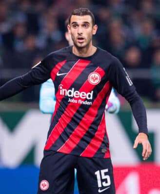 Soccer player in Eintracht Frankfurt kit with number 15, standing near the goal during a match.