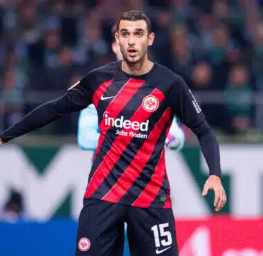 Soccer player in Eintracht Frankfurt kit with number 15, standing near the goal during a match.