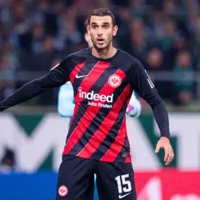 Soccer player in Eintracht Frankfurt kit with number 15, standing near the goal during a match.