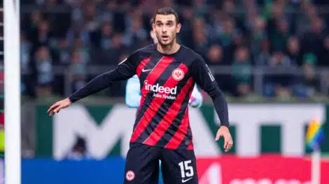 Soccer player in Eintracht Frankfurt kit with number 15, standing near the goal during a match.