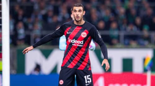 Soccer player in Eintracht Frankfurt kit with number 15, standing near the goal during a match.