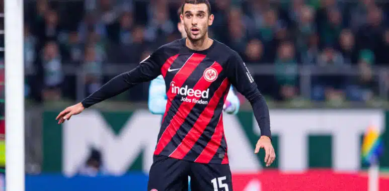 Soccer player in Eintracht Frankfurt kit with number 15, standing near the goal during a match.