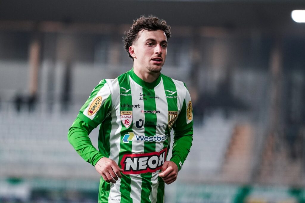 delaye-sascha-austria-lustenau-vs-first-vienna-06-03-2026-lb-photo-com-luka-kolanovic-biereder | AllezPaillade.com Male soccer player in a green and white striped jersey running on the field during a match accessible for screen readers.