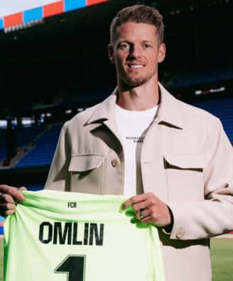 Football player on a stadium field holding a neon green jersey that reads 'OMLIN' and number 1, smiling at camera.