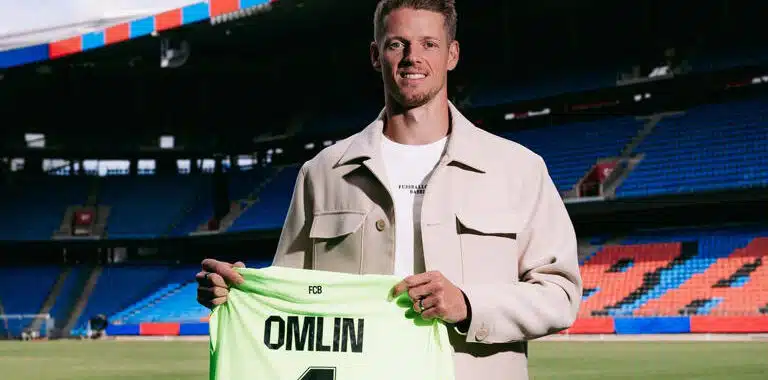 omlin bâle | AllezPaillade.com Football player on a stadium field holding a neon green jersey that reads 'OMLIN' and number 1, smiling at camera.